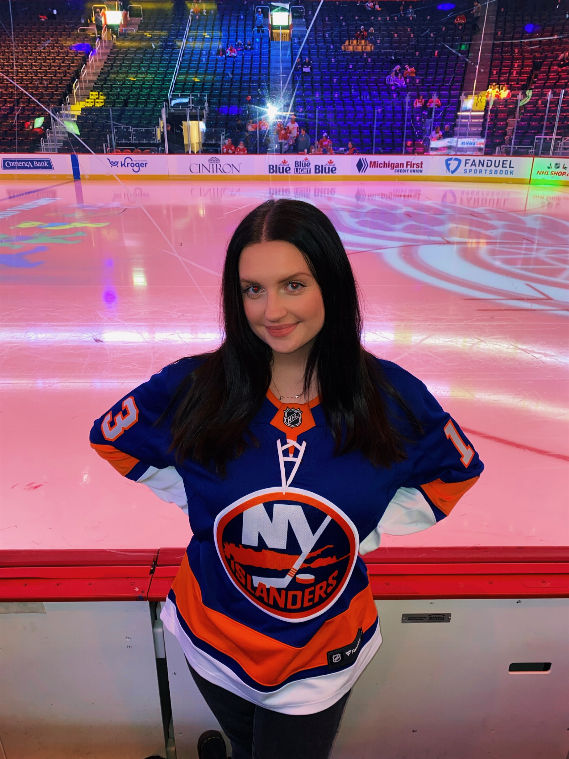 Woman in hockey jersey stands in front of ice rink