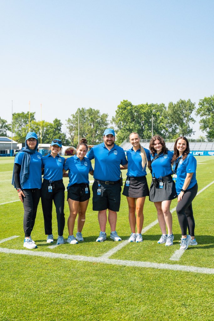 seven people standing arm in arm on a football field 