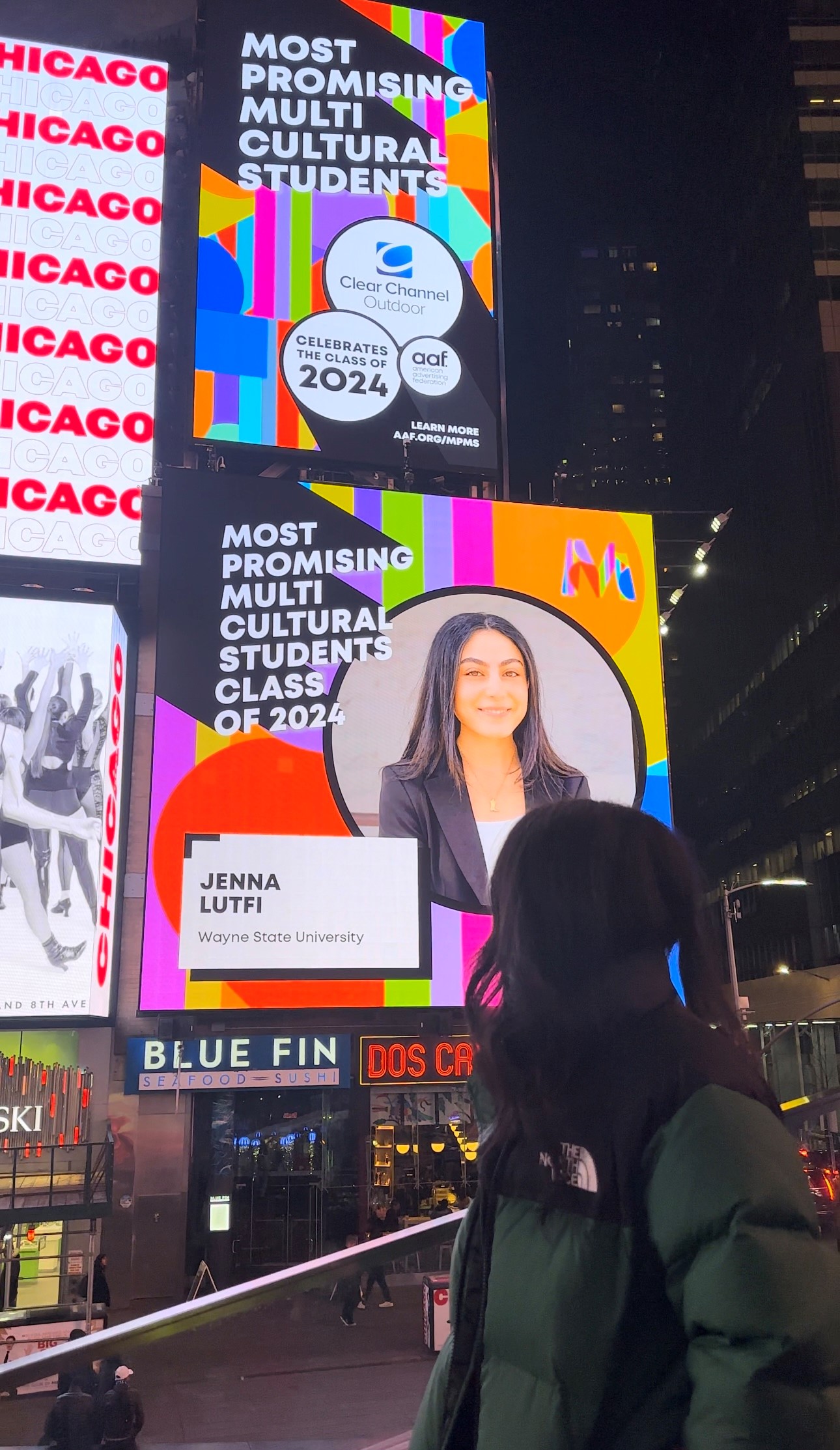 Woman looking at a public digital sign with her photo displayed next to the title Most Promising Multicultural Students Class of 2024