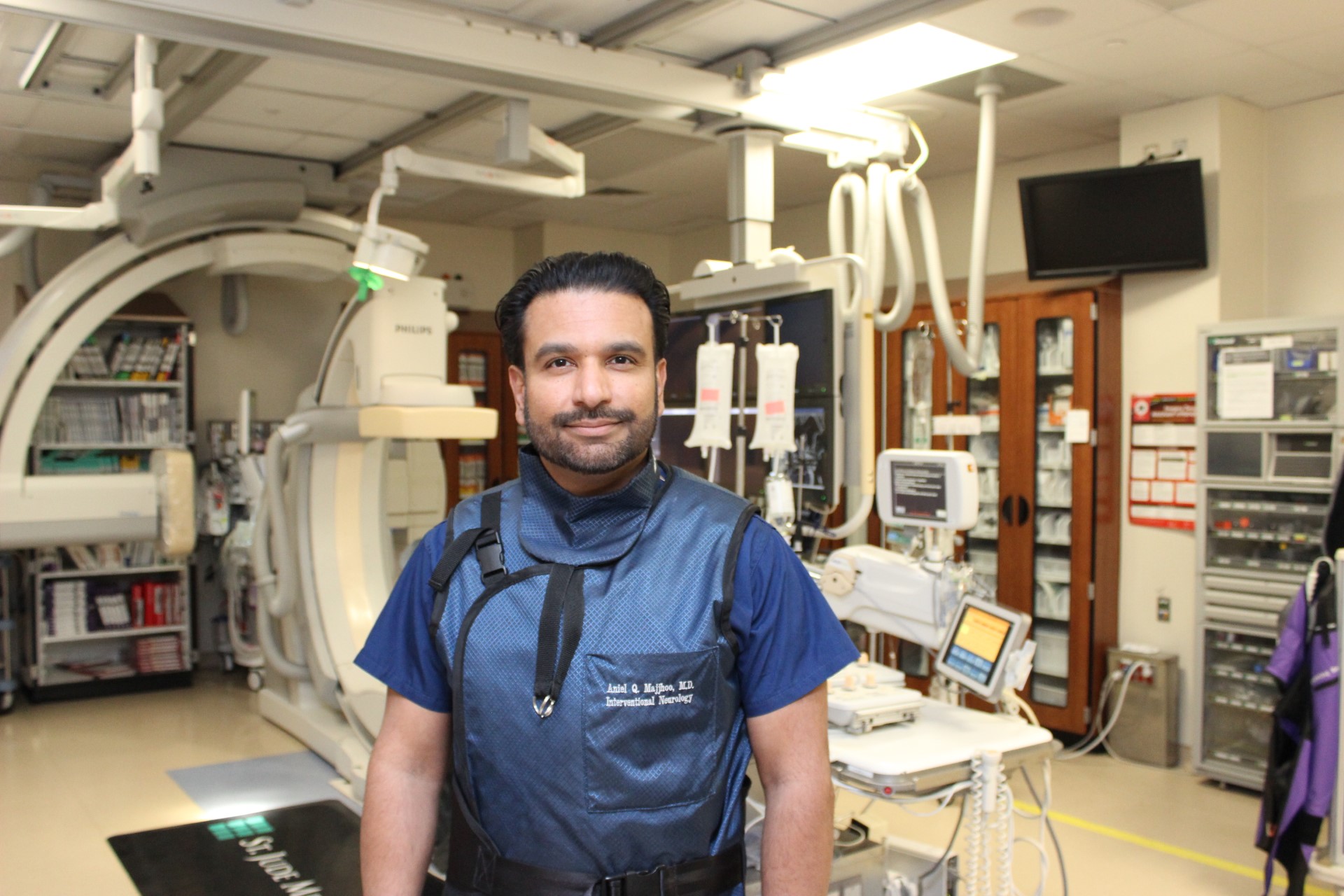 A man in surgical scrubs standing in front of a surgery bay 